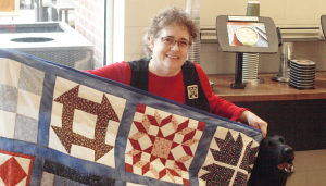Laurie Leonard poses with her rendition of an underground railroad code quilt. Legend says quilts like these were put out to help lead escaped slaves to the North and freedom.