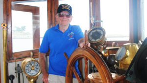 Volunteer Mike Brown at wheelhouse of U.S. Army LT-5 (Large Tug) at H. Lee White Maritime Museum in Oswego.