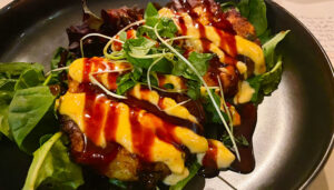 Hearty crab cakes at Kaisai sit on a bed of greens dressed in eel sauce and Ssamjang (spicy Korean paste) aioli.